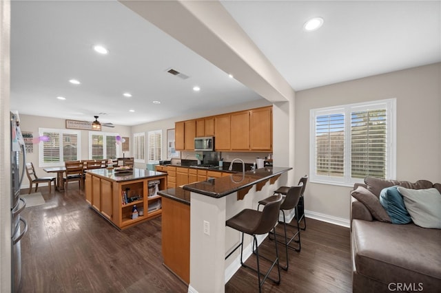 kitchen featuring recessed lighting, stainless steel microwave, baseboards, visible vents, and dark wood-style floors