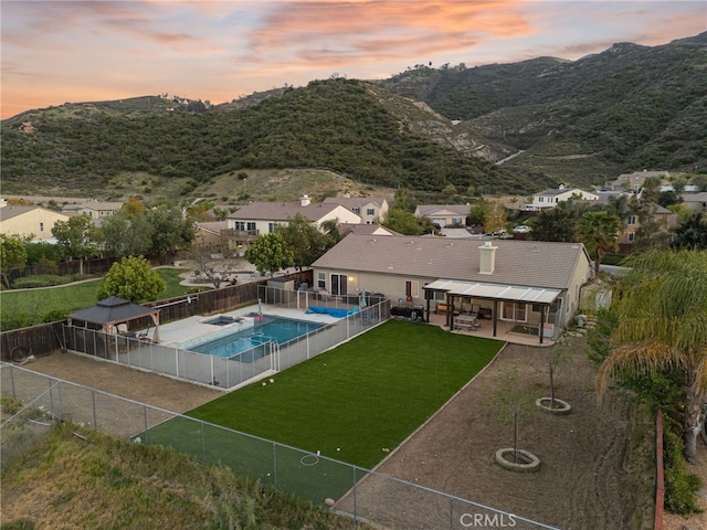 view of pool featuring a fenced backyard, a fenced in pool, a patio area, a mountain view, and a yard