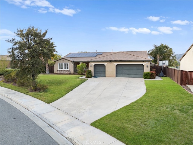 ranch-style house with fence, an attached garage, a front yard, roof mounted solar panels, and concrete driveway