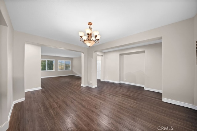 unfurnished dining area featuring baseboards, a chandelier, and dark wood-type flooring