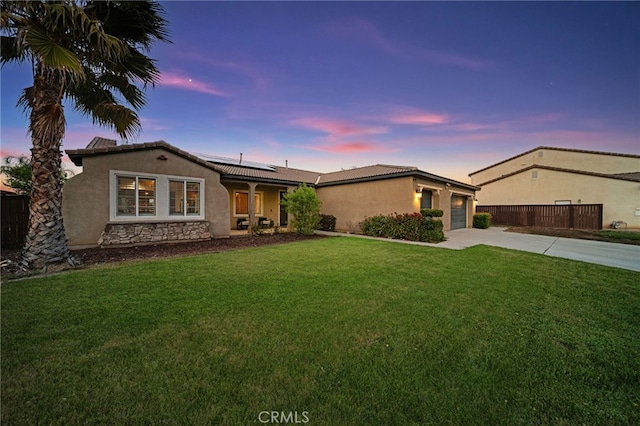 ranch-style house with a front lawn, roof mounted solar panels, stucco siding, and driveway