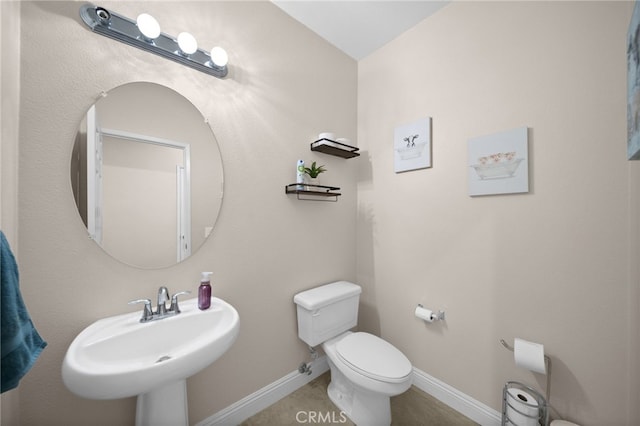 half bath featuring a sink, baseboards, and toilet