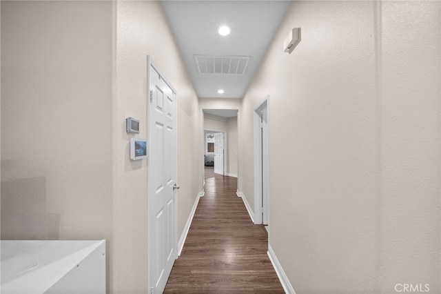 hall with visible vents, recessed lighting, dark wood-style flooring, and baseboards