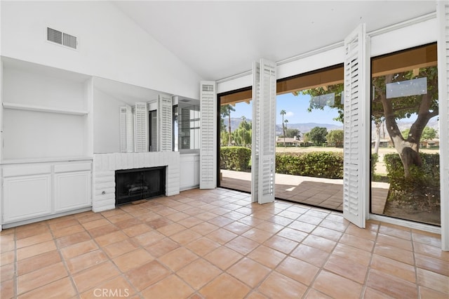 unfurnished living room with light tile patterned floors, a fireplace, and high vaulted ceiling