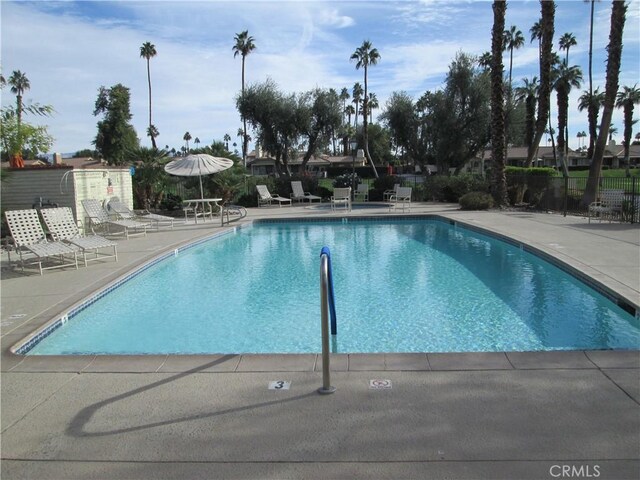 community pool with a patio and fence