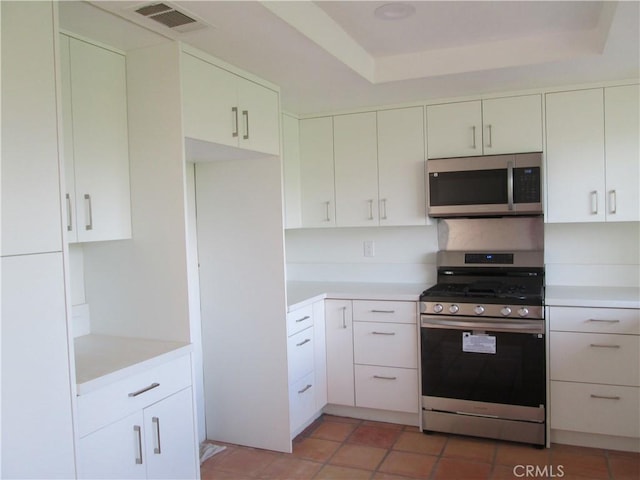 kitchen featuring appliances with stainless steel finishes, light countertops, a tray ceiling, and white cabinetry