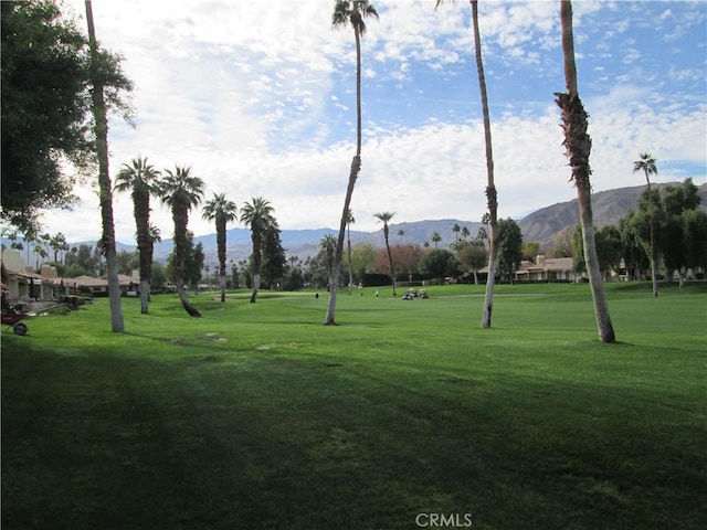 view of property's community featuring a mountain view, a lawn, and golf course view