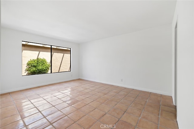 unfurnished room with light tile patterned flooring and baseboards