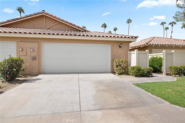 view of front of house with driveway, stucco siding, fence, and a garage