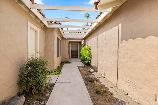 view of home's exterior with stucco siding and a pergola