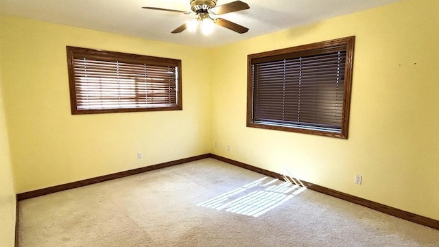 carpeted empty room with baseboards and a ceiling fan