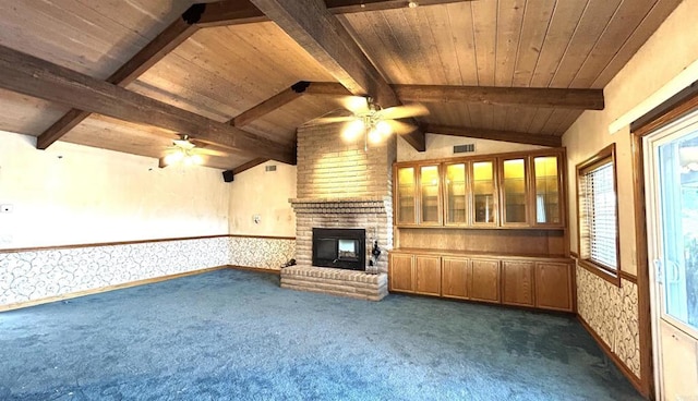 unfurnished living room with lofted ceiling with beams, a ceiling fan, a brick fireplace, and dark colored carpet
