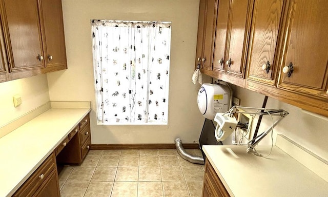 clothes washing area featuring light tile patterned flooring, baseboards, and cabinet space