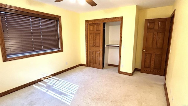 unfurnished bedroom with a closet, baseboards, ceiling fan, and light carpet