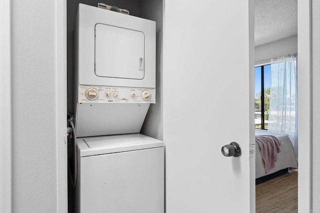 5170 Clairemont Mesa Blvd Unit 27, San Diego, CA 92117 - laundry area featuring stacked washing machine and dryer, wood finished floors, and a textured ceiling