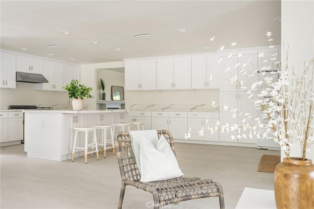 19201 Barrett Ln, North Tustin, CA 92705 - kitchen with under cabinet range hood, white cabinetry, a breakfast bar area, and refrigerator