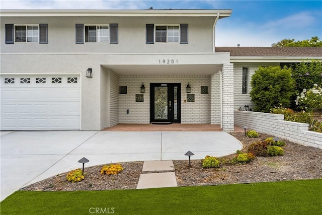 19201 Barrett Ln, North Tustin, CA 92705 - view of front facade featuring brick siding, a porch, stucco siding, and concrete driveway