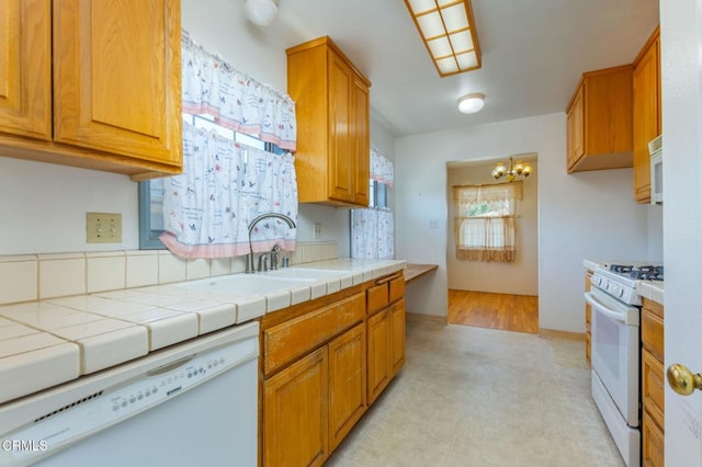 kitchen featuring a sink, brown cabinets, a chandelier, and white appliances