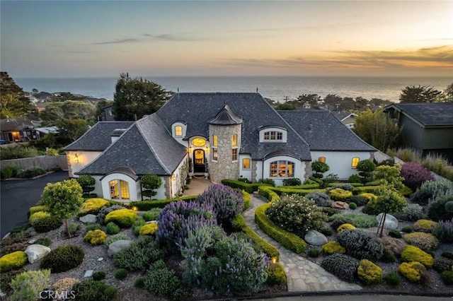 french country style house with a water view and stone siding