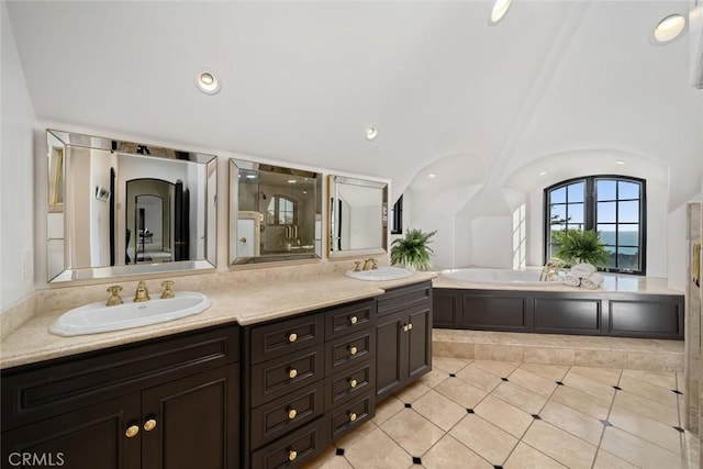 full bathroom featuring a sink, tile patterned floors, double vanity, and a garden tub