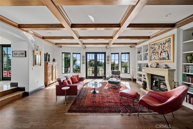 living area featuring coffered ceiling, beam ceiling, a glass covered fireplace, and plenty of natural light