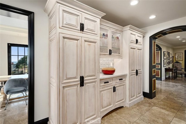 interior space featuring crown molding, baseboards, recessed lighting, and arched walkways