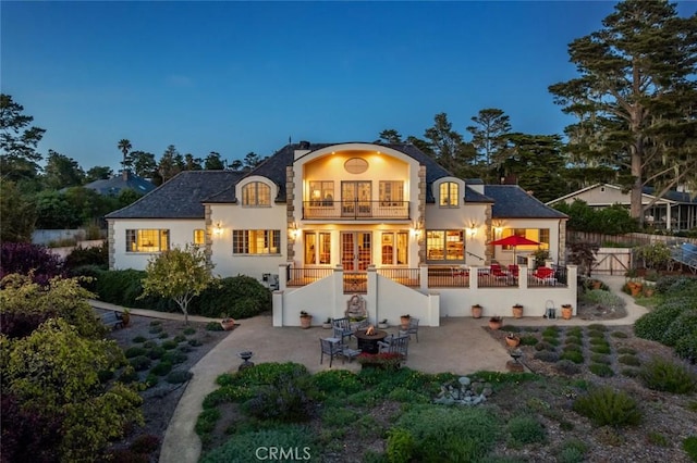 rear view of house with a patio, french doors, stucco siding, and a balcony
