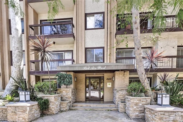 property entrance with a balcony and stucco siding