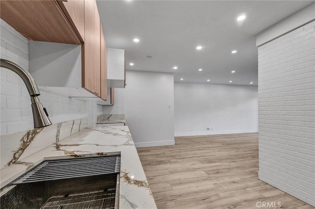 kitchen with light wood-type flooring, light stone counters, and recessed lighting