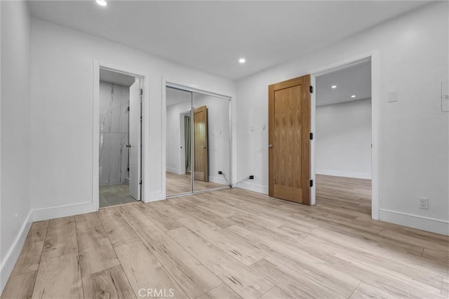 unfurnished bedroom featuring a closet, wood finished floors, baseboards, and recessed lighting