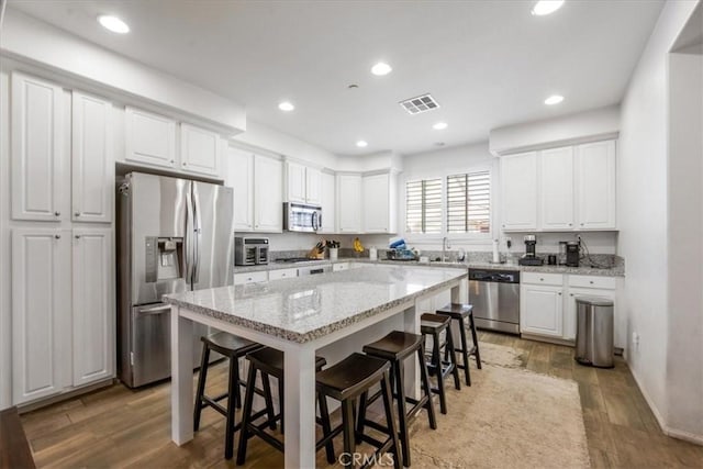 40925 Lacroix Ave, Murrieta, CA 92562 - kitchen with a breakfast bar area, white cabinetry, visible vents, and stainless steel appliances
