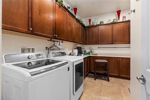 washroom featuring cabinet space, light tile patterned floors, and washing machine and dryer