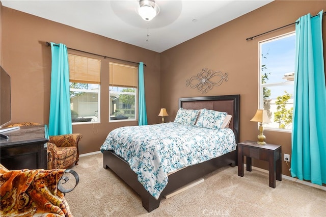 carpeted bedroom featuring multiple windows, baseboards, and ceiling fan