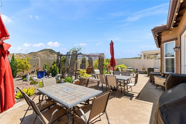 view of patio / terrace with outdoor dining area, a fenced backyard, cooling unit, and a mountain view