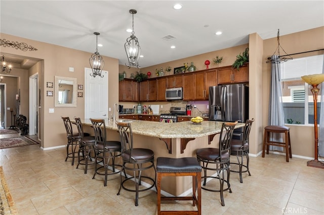 kitchen with visible vents, baseboards, a notable chandelier, stainless steel appliances, and a breakfast bar area