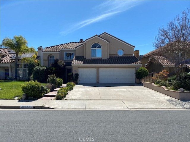 mediterranean / spanish home with a tiled roof, an attached garage, driveway, and stucco siding