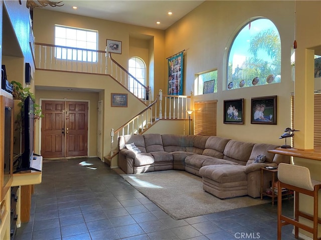 tiled living room with recessed lighting, a towering ceiling, and stairs