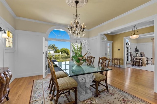 1239 S Patton Ave, San Pedro, CA 90731 - dining area featuring light wood-type flooring, a chandelier, crown molding, and a decorative wall
