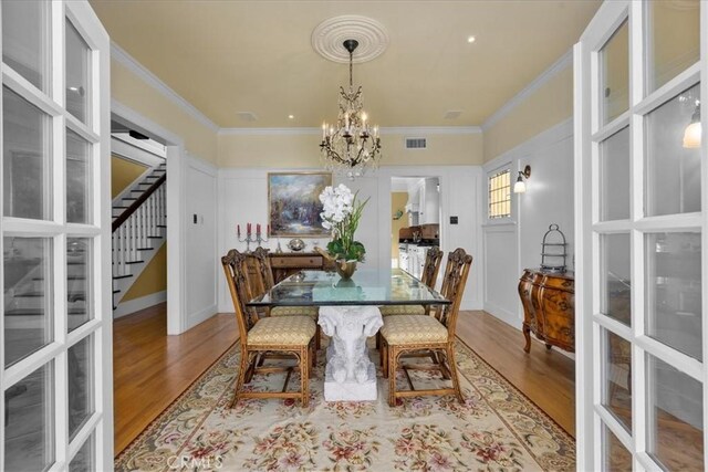 1239 S Patton Ave, San Pedro, CA 90731 - dining area featuring a chandelier, stairway, wood finished floors, ornamental molding, and french doors
