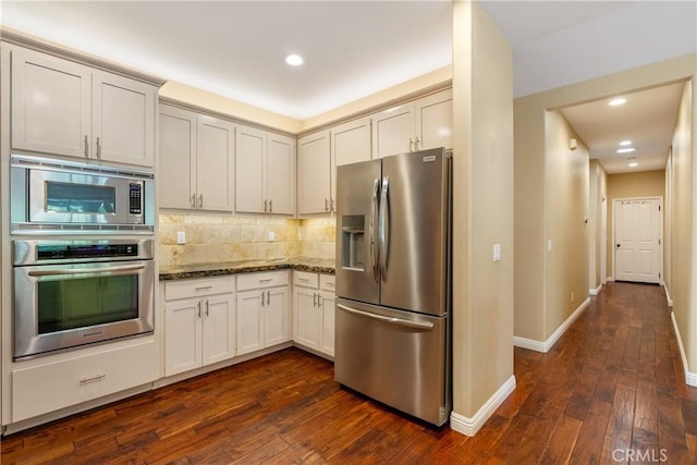 kitchen with tasteful backsplash, dark stone countertops, stainless steel appliances, dark wood-type flooring, and recessed lighting