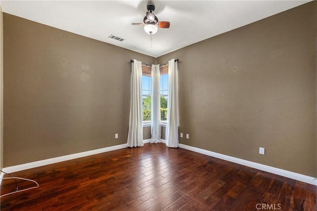 empty room featuring wood finished floors, visible vents, baseboards, and ceiling fan