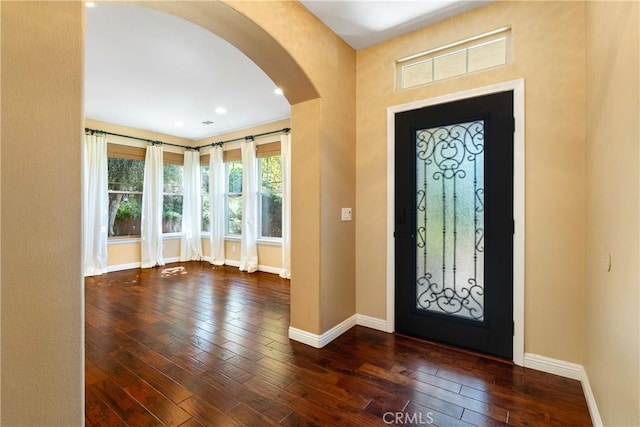 foyer entrance with hardwood / wood-style flooring, baseboards, and arched walkways