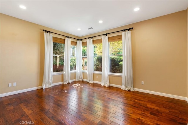 unfurnished room featuring visible vents, hardwood / wood-style flooring, and baseboards