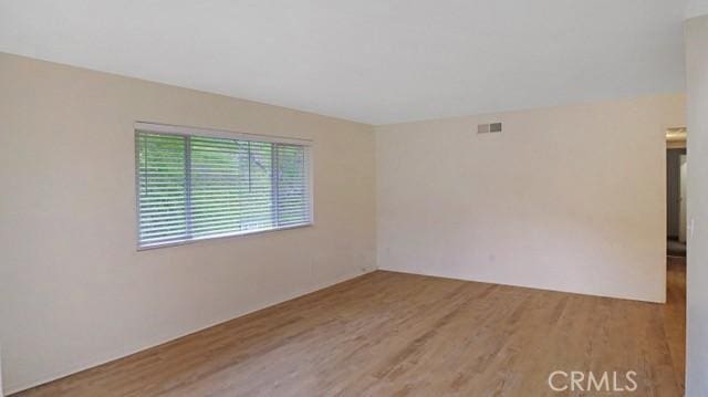 unfurnished room with wood finished floors and visible vents