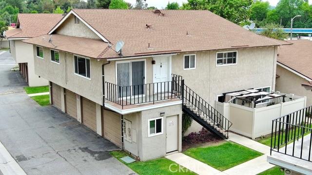 rear view of property featuring a garage, driveway, stairs, and stucco siding
