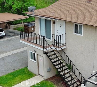 doorway to property featuring a shingled roof and stucco siding