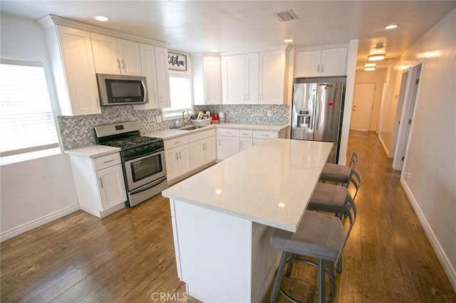 kitchen with backsplash, baseboards, appliances with stainless steel finishes, and a kitchen bar