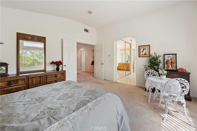 carpeted bedroom featuring arched walkways, visible vents, ensuite bath, and lofted ceiling