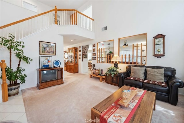 living room with stairway, a towering ceiling, visible vents, and carpet