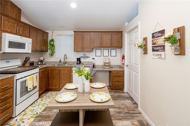 kitchen featuring visible vents, light stone countertops, a sink, light wood-style floors, and white appliances